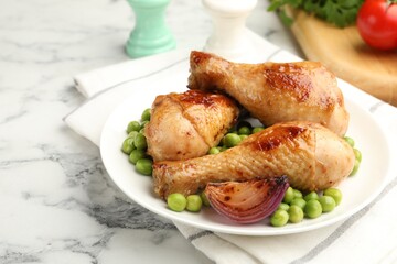 Grilled chicken drumsticks served with green peas on white marble table, closeup. Space for text