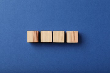 Wooden cubes on blue background, top view