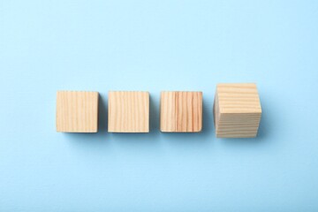 Wooden cubes on light blue background, top view