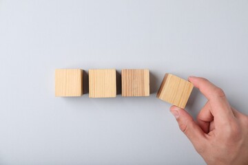 Man with wooden cubes on light background, top view
