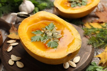 Tasty pumpkin cream soup with seeds and parsley on wooden table, closeup