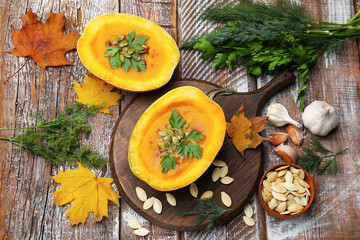 Tasty pumpkin cream soup with seeds, parsley, dill and autumn leaves on color wooden table, flat lay