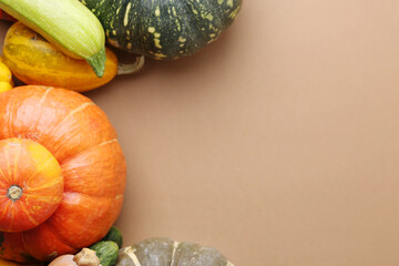 Many fresh pumpkins and other vegetables of gourd family on beige background, flat lay. Space for...