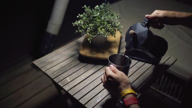 caf&eacute; en taza met&aacute;lica sobre una mesa de madera de noche en el exterior de una caba&ntilde;a