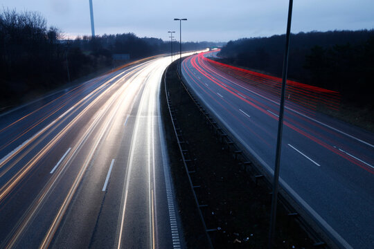 Denmark - Long exposure captures light trails from vehicles on a multi-lane highway at dusk, showcasing the blur of motion.