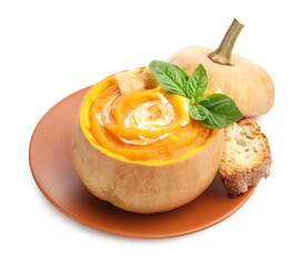 Tasty pumpkin cream soup with basil and bread served in pumpkin isolated on white