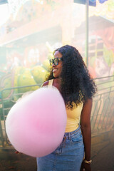 Young woman smiling while holding pink cotton candy at a fair