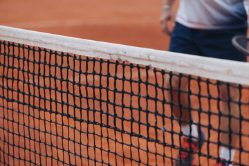 Tennis tournament championship on outdoor clay court with net, professional athletes play in motion with rackets serve tennis ball during tennis match game, tennis training in a sunny day on a stadium