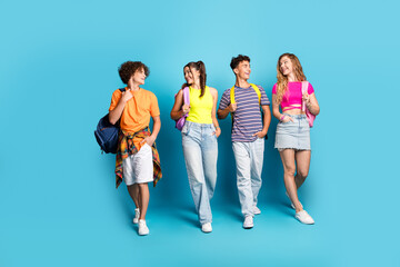 Fototapeta premium Funny fresh friends walk together in bright outfits against a blue backdrop