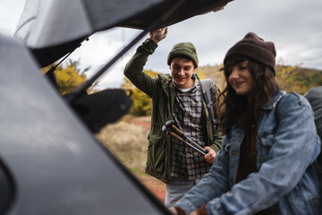 Couple preparing hiking gear from car trunk for fall adventure