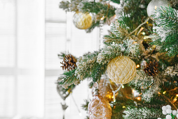 Snowy frosted Christmas tree branch with festive lights and decorative gold and silver ornaments...