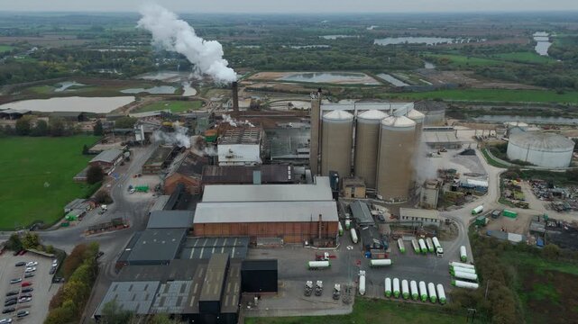 Aerial drone view of industrial sugar factory near Newark United Kingdom with silos, chimneys emitting smoke, food processing and manufacturing plant