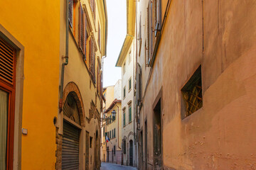 Medieval narrow street in Florence city with cobblestone and yellow buildings, Tuscany, Italy. Firenze old town. Italian architecture