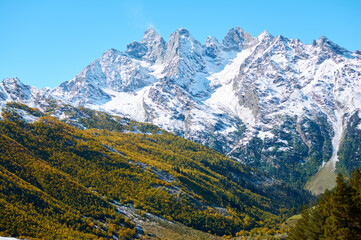 A stunning contrast in Gwandra where snow-capped peaks pierce the blue sky while the foreground valley blazes with autumn's golden embrace.