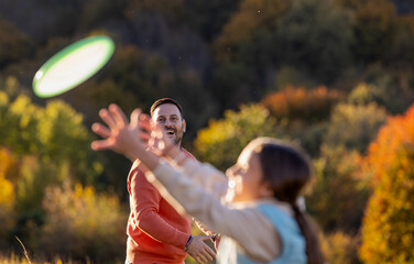 Family playing frisbee in a sunny field during afternoon