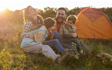 Family enjoying laughter in nature near a tent