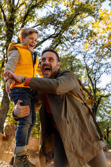 Joyful father and son play in autumn park