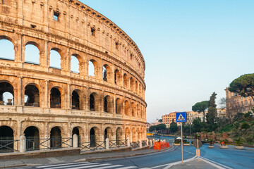 Side view of ancient Roman Colosseum Amphitheater in Rome city, Italy at sunrise with empty streets. Italian architecture. Popular touristic and travel landmark