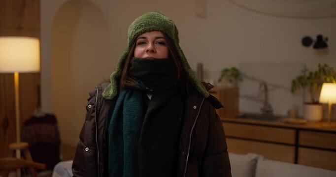 A woman prepares for the cold by putting on multiple layers of warm clothing and getting ready for winter walk