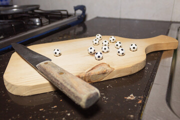 Mini soccer balls and knife on a wooden cutting board on a modern kitchen countertop