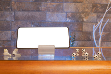 Cell phone with blank screen surrounded by mini soccer balls in a living room. Online gaming broadcast
