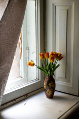 a vase of tulips on an old windowsill