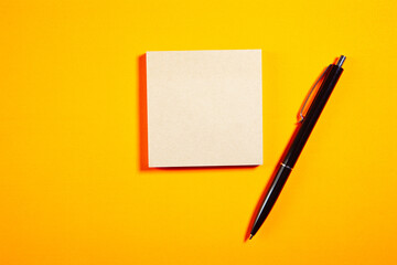 Blank business card and pen on orange background. Top view with copy space