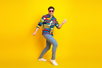 Young handsome male model dancing in a colorful print shirt against yellow background for lifestyle fashion and advertising photography