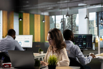 Business people gathered around laptops working on project tasks and targets for development....