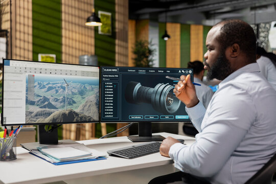 Engineer in office analyzes wind turbine component to improve renewable energy efficiency. RD department specialist uses CAD software to refine turbine part design, boosting clean energy output