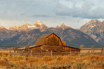 The iconic antique T.A. Moulton barn in Grand Teton National Park at Sunrise with Grand Teton and the snowcapped mountains of the Teton Range behind the field