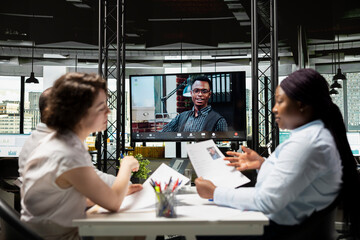Black young applicant chatting with recruiting team during remote interview via video conference, exploring experience and qualifications to ensure alignment with position requirements.