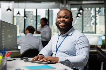 Portrait of smiling sustainability specialist in office evaluating environmental impact of wind turbine. Happy worker reviews turbine performance data to find ways to save energy and lower costs