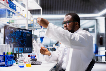 Histology technician in research facility using colorful chemical solutions in test tubes....