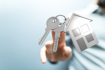 Conceptual image of a hand holding keys with a house charm, representing home ownership, real estate, and the dream of a new home. Perfect for p