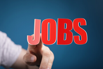 Hand reaching out to touch the word JOBS, representing job searching, opportunity, and career development. Conceptual image for employment, hiri