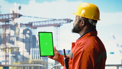 Green screen tablet used by energy production company expert to determine optimal drilling rig locations. Engineer on offshore platform deck looking at well sites data on chroma key device,