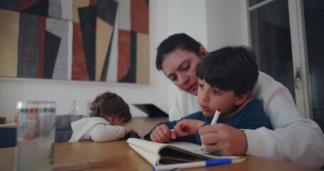Mother drawing together with son at dining table while toddler sibling rests head on arm nearby, highlighting family bonding and tender connection in everyday home life - Powered by Adobe