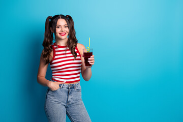 Young stylish woman holding a drink and smiling with a vibrant background emphasizing cheerful and casual lifestyle