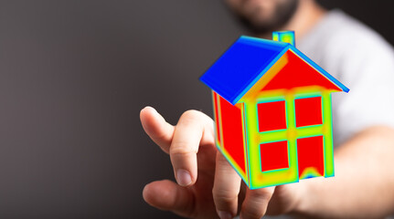 A person's hand holding a colorful 3D house model, symbolizing home finance, energy efficiency, and...