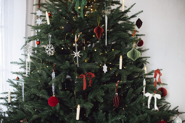 Stylish Christmas tree with modern paper baubles, bows, ornaments, vintage stars, lights and...
