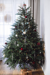 Stylish Christmas tree with modern paper baubles, ornaments, vintage stars, lights and gift boxes...