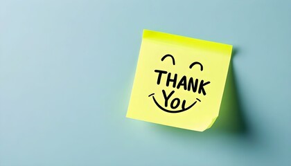 A yellow sticky note with a handwritten 'Thank You' message and a smiling face, stuck on a light blue wall.