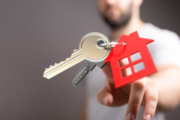 A hand presenting a key with a house tag, symbolizing homeownership, property investment, and the...