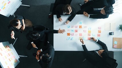 Top down view of professional business team working together to share idea while using colorful sticky note at whiteboard. Diverse project manager choosing or planning marketing strategy. Directorate.