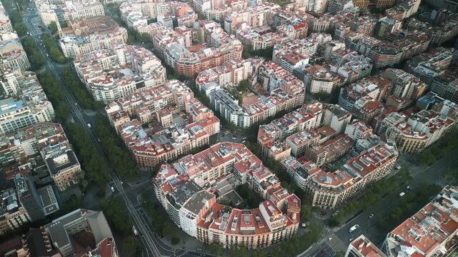 4K drone aerial view of Eixample district in Barcelona, Spain, showing iconic grid city layout, geometric blocks and tree-lined streets on a sunny day