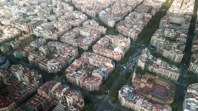 4K drone aerial view of Eixample district in Barcelona, Spain, showing iconic grid city layout, geometric blocks and tree-lined streets on a sunny day