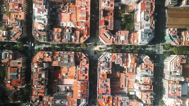 4K drone aerial view of Eixample district in Barcelona, Spain, showing iconic grid city layout, geometric blocks and tree-lined streets on a sunny day
