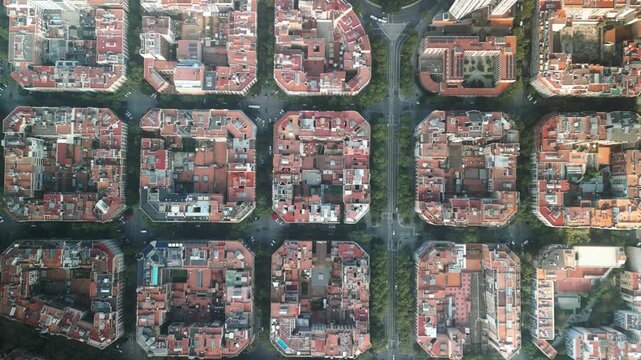 4K drone aerial view of Eixample district in Barcelona, Spain, showing iconic grid city layout, geometric blocks and tree-lined streets on a sunny day