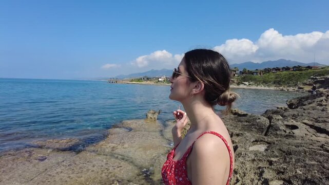 The young woman smokes a cigarette and chats with the people next to her at the seaside, where they took a break on the way to holiday.